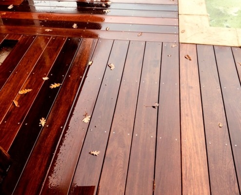 DECKiBOIS Terrasse en bois exotique ipé 21 x 145 mm affleurant une margelle en pierre avec un changement de sens des lames ( photo prise sous la pluie )
