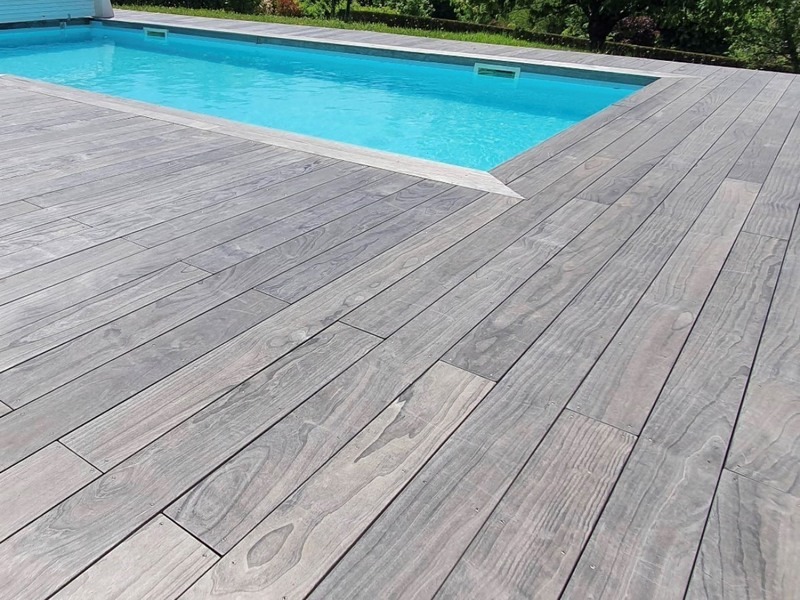 Le contour de cette piscine en France a été agrémenté de lames de terrasse Accoya Color gris teinté dans la masse Le contour de cette piscine en France a été agrémenté de lames de terrasse Accoya Color gris teinté dans la masse